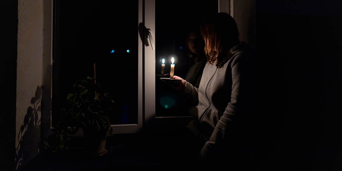 resident holds up candle during storm power outage